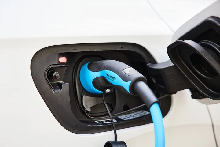 Câble de recharge bleu avec connecteur Type 2 branché dans la trappe de recharge d'une voiture blanche