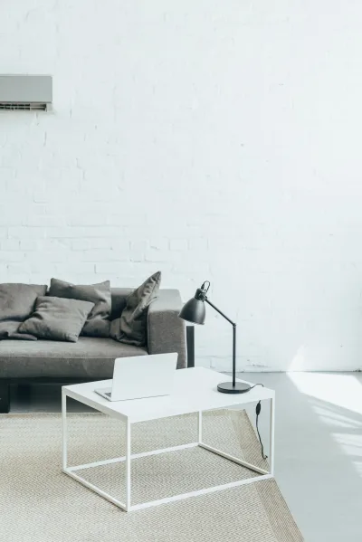 Salon lumineux avec canapé gris, table basse blanche et climatiseur mural au-dessus
