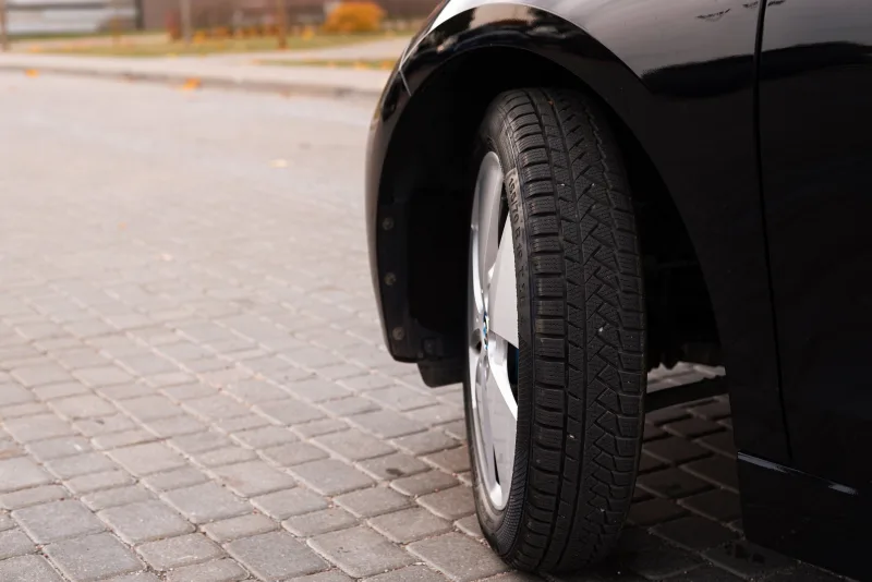 Pneu d'une voiture noire sur un sol pavé