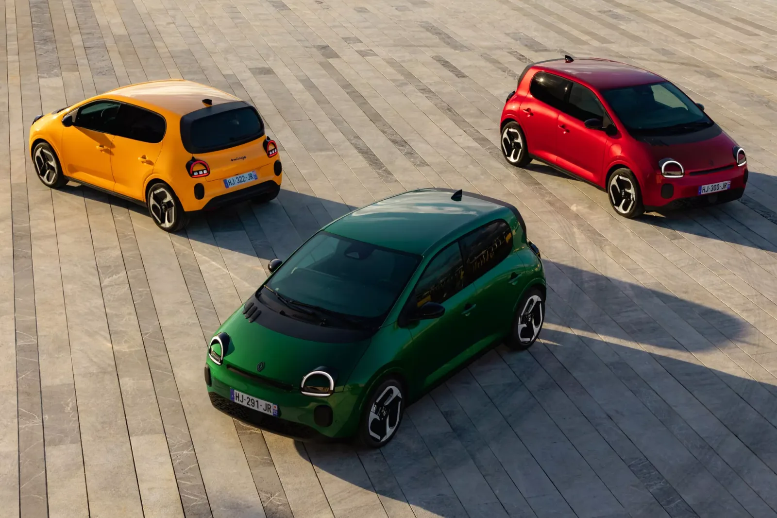 Trois Twingo E-Tech electric (jaune Mango, rouge, vert) vues de dessus sur une esplanade