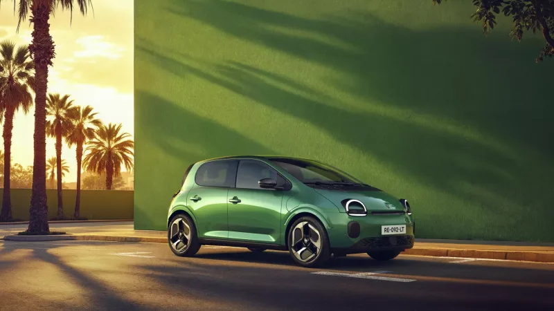 Renault Twingo E-Tech electric verte devant un mur vert et des palmiers au coucher du soleil