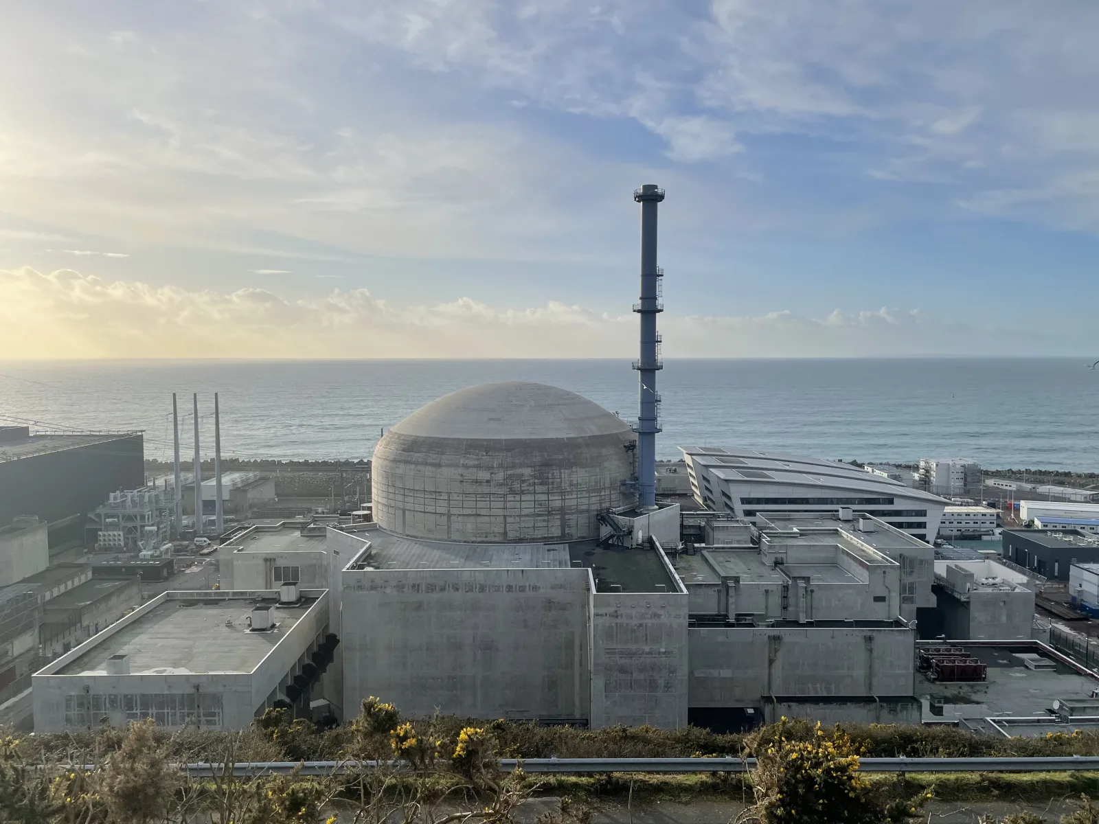 Dôme du réacteur EPR de Flamanville 3 face à la mer, avec la cheminée bleue