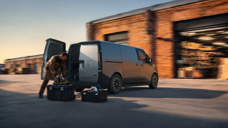 Artisan déchargeant des caisses à outils d'un Trafic Van E-Tech electric porte arrière ouverte