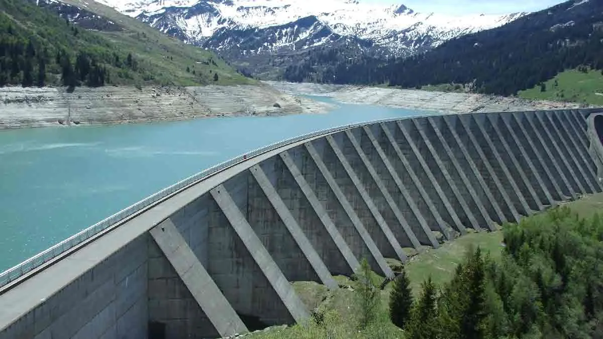 Barrage-voûte à contreforts retenant un lac de montagne aux eaux turquoise